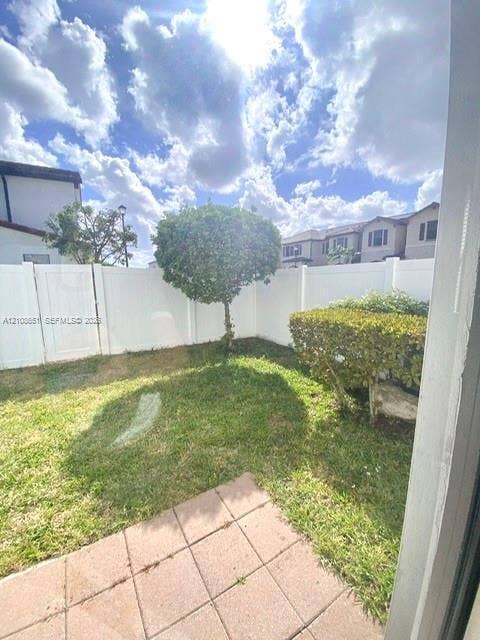 3288 W 106th Terrace, #3288, Hialeah, Hialeah, FL 33018 Enclosed backyard featuring a concrete paver patio, manicured lawn, established landscaping, and white vinyl perimeter fencing