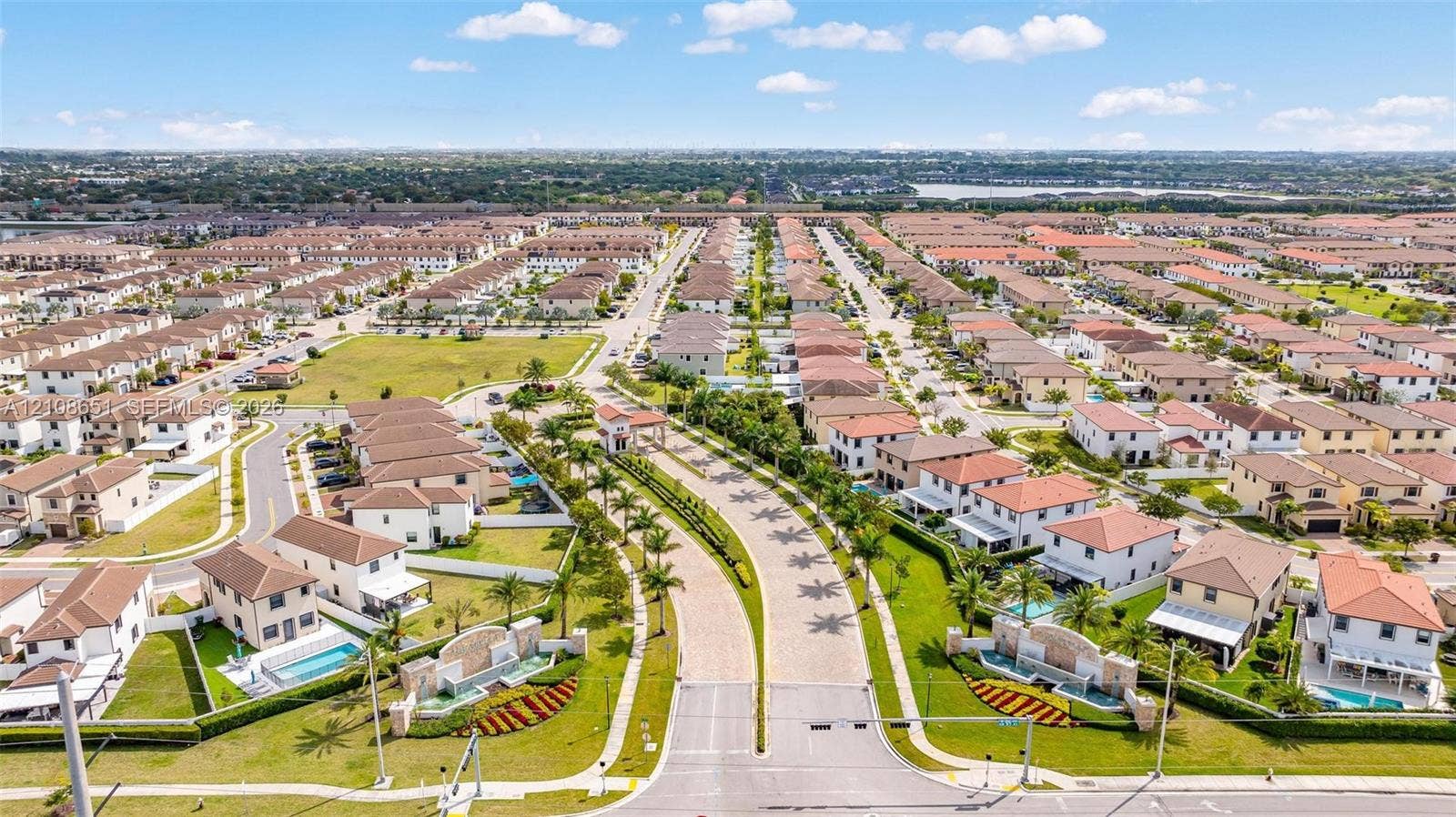 3288 W 106th Terrace, #3288, Hialeah, Hialeah, FL 33018 Aerial perspective of a residential community featuring paver-surfaced roadways, landscaped entry monuments with water features, tree-lined thoroughfares, and private swimming pools