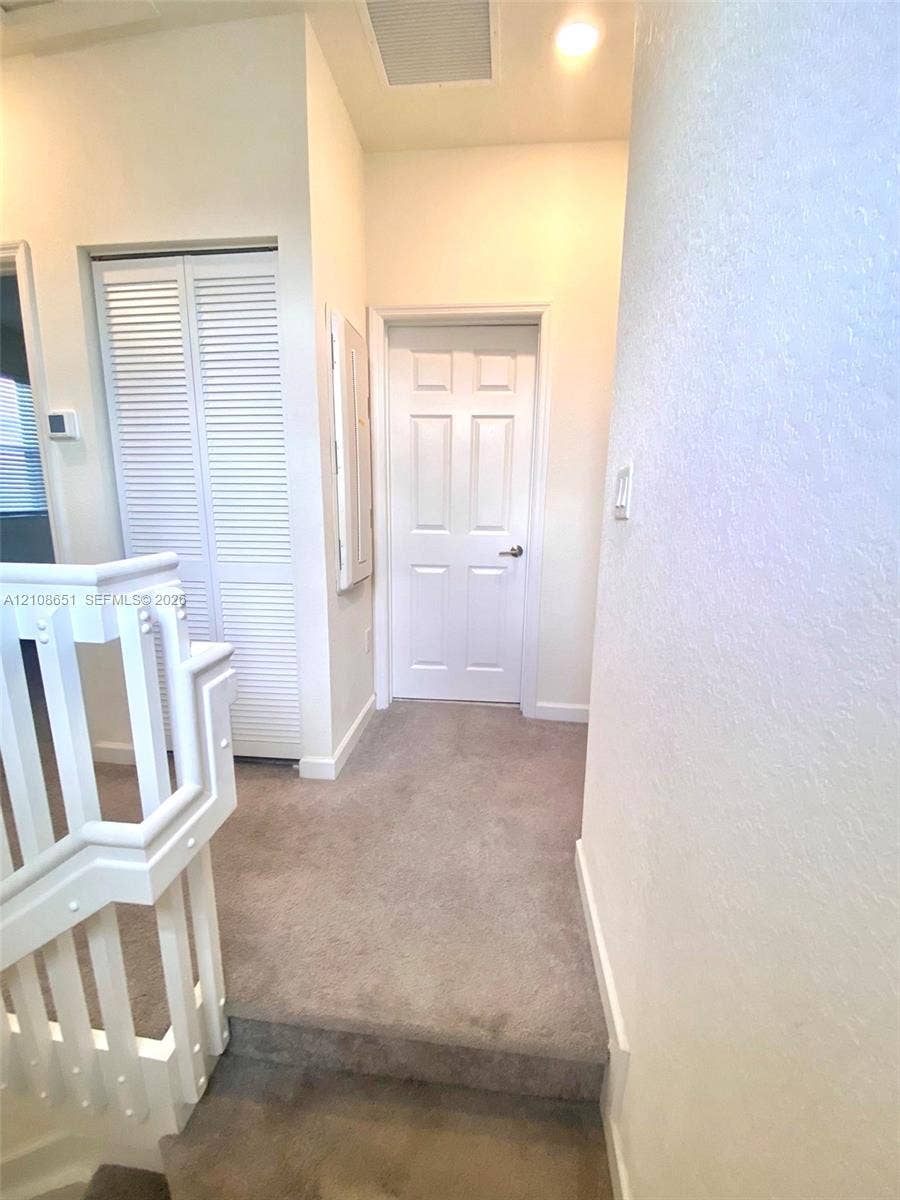 3288 W 106th Terrace, #3288, Hialeah, Hialeah, FL 33018 Neutral-toned carpeted flooring, white six-panel interior door, and bi-fold louvered closet doors featuring a white finish