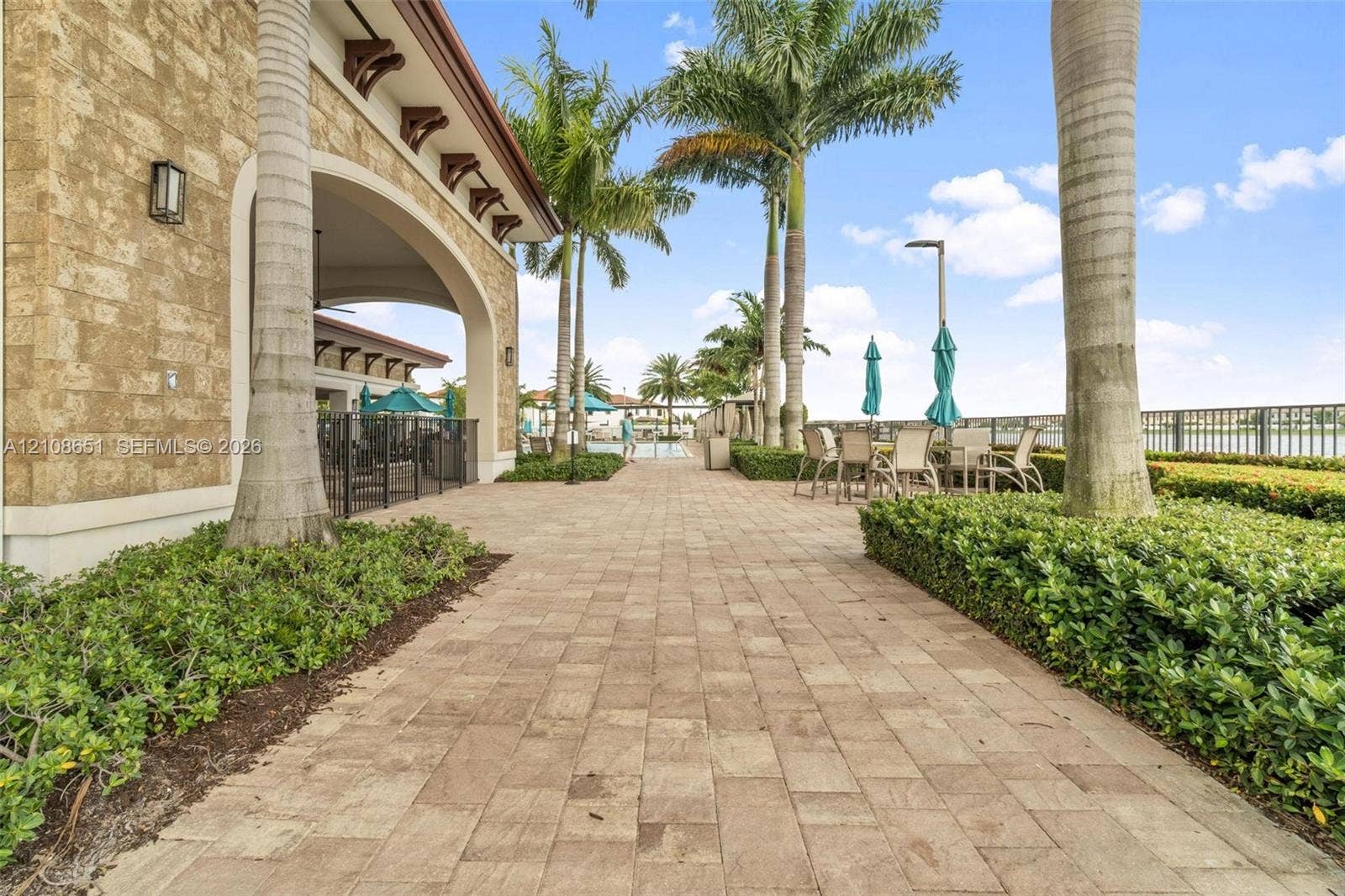 3288 W 106th Terrace, #3288, Hialeah, Hialeah, FL 33018 Paver stone walkway featuring a masonry exterior, covered loggia, and landscaped perimeter with mature palm trees