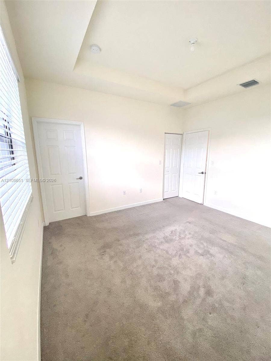 3288 W 106th Terrace, #3288, Hialeah, Hialeah, FL 33018 Interior space featuring a recessed tray ceiling, wall-to-wall carpeting, and two six-panel interior doors