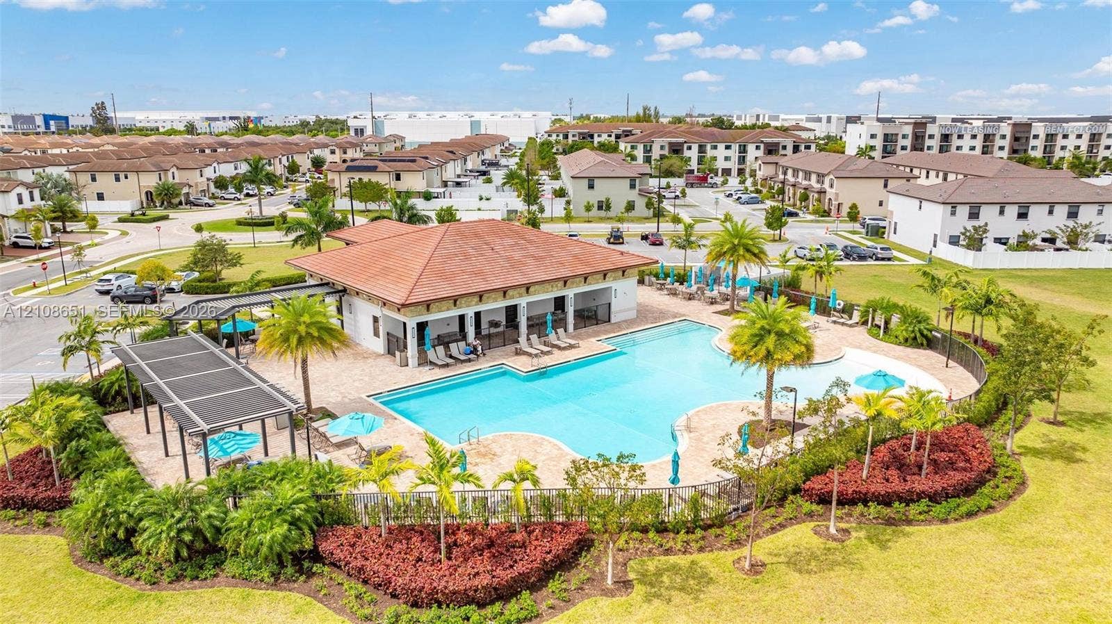 3288 W 106th Terrace, #3288, Hialeah, Hialeah, FL 33018 Community amenity area featuring a swimming pool, covered pavilion with shingle roof, expansive paver deck, and manicured landscaping