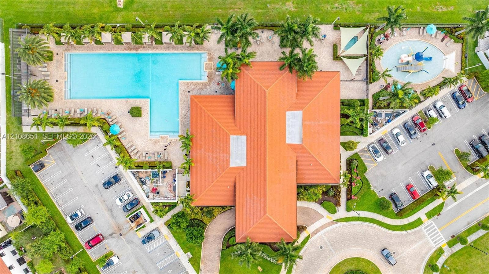 3288 W 106th Terrace, #3288, Hialeah, Hialeah, FL 33018 Aerial view of property complex featuring a large swimming pool, a separate children's splash pool, terracotta-style roof tile, and paved parking areas