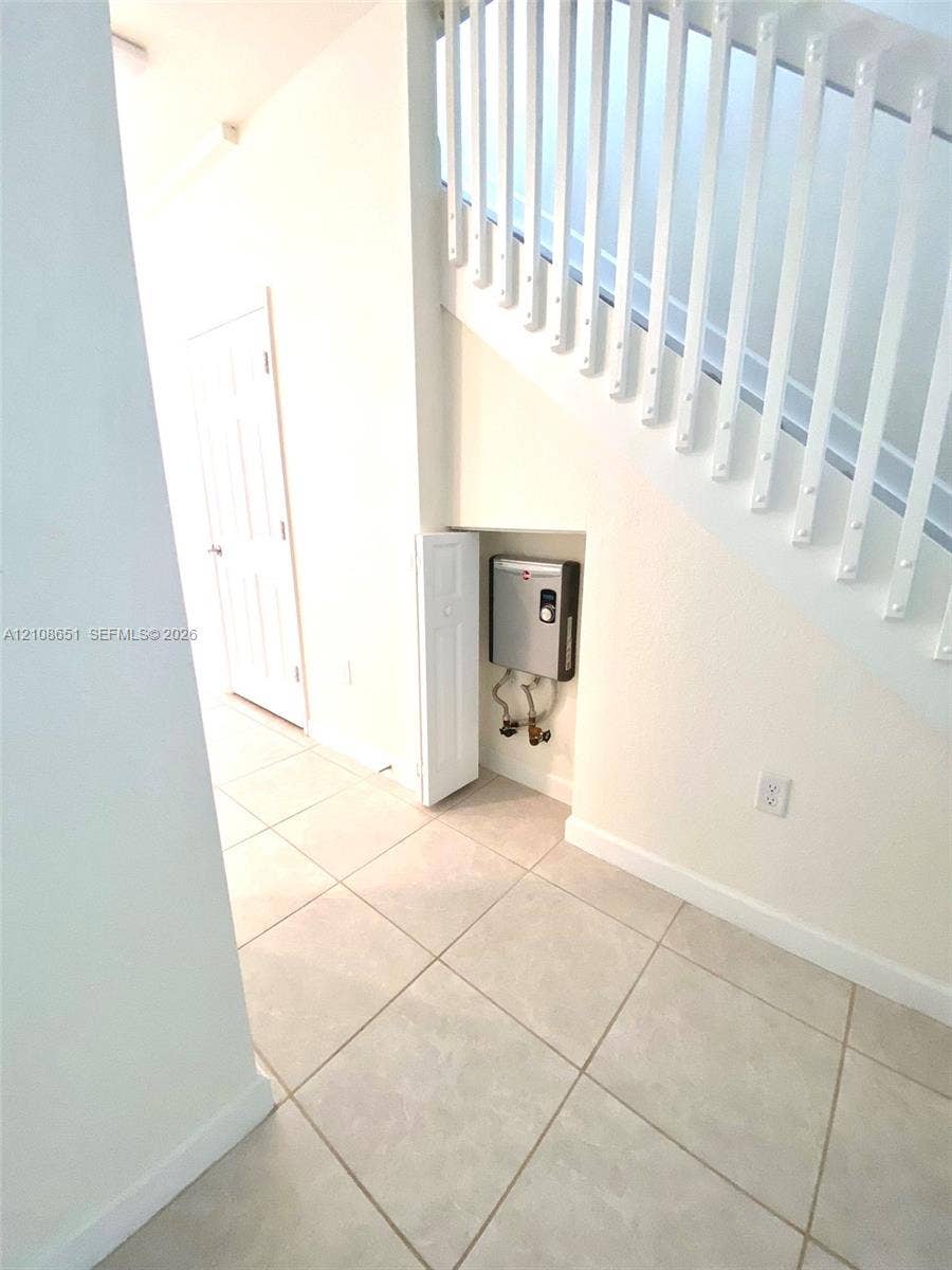 3288 W 106th Terrace, #3288, Hialeah, Hialeah, FL 33018 Staircase featuring white balusters and a handrail, ceramic tile flooring, and a recessed storage area housing a tankless water heater