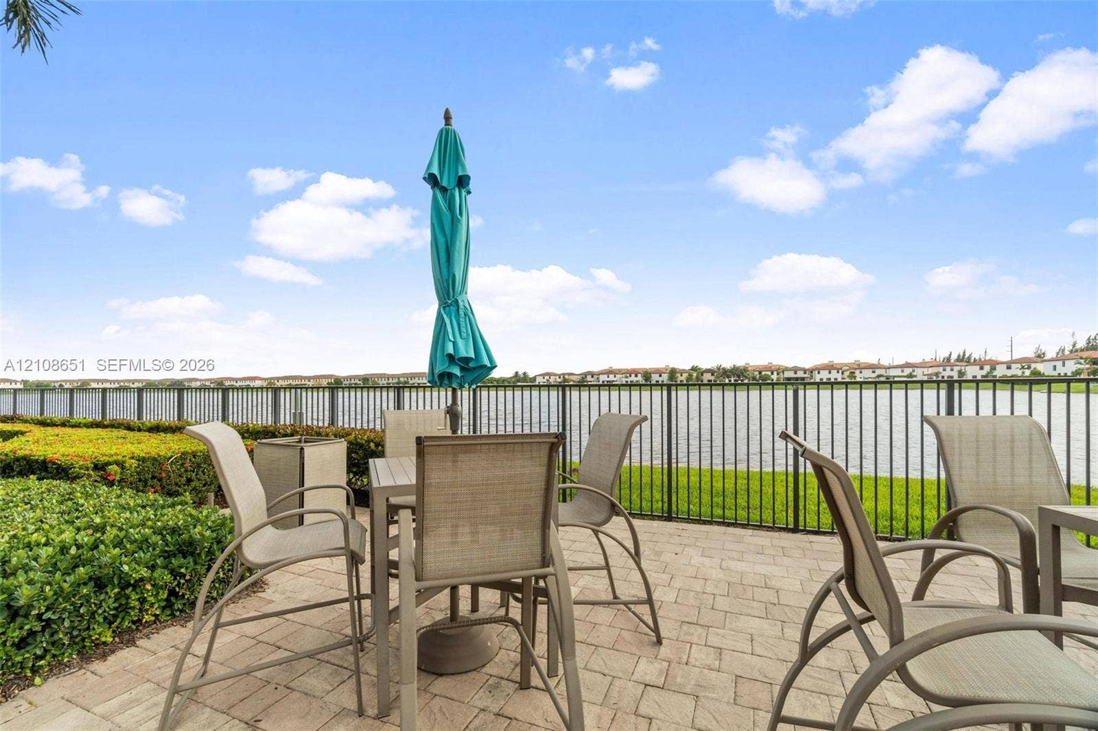 3288 W 106th Terrace, #3288, Hialeah, Hialeah, FL 33018 Paver patio featuring a perimeter metal fence, manicured landscaping, and direct water frontage