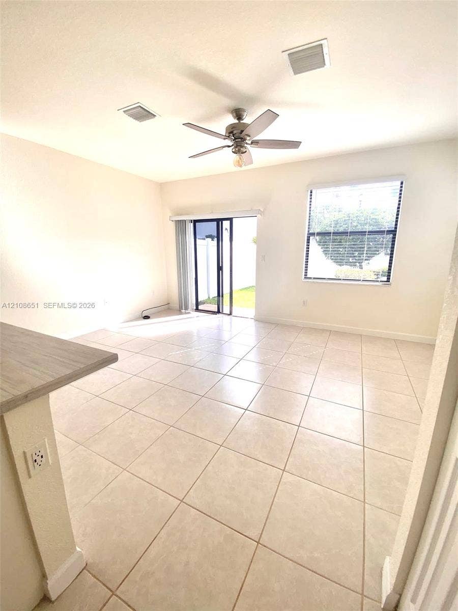 3288 W 106th Terrace, #3288, Hialeah, Hialeah, FL 33018 Open floor plan featuring large-format ceramic tile flooring, a central ceiling fan, sliding glass doors, and a single-pane window