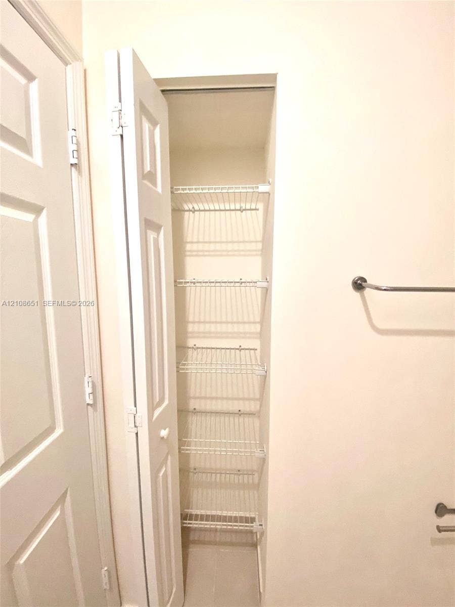 3288 W 106th Terrace, #3288, Hialeah, Hialeah, FL 33018 Built-in storage closet featuring five tiered wire shelves, a white paneled bifold door, and a horizontal wall-mounted towel bar