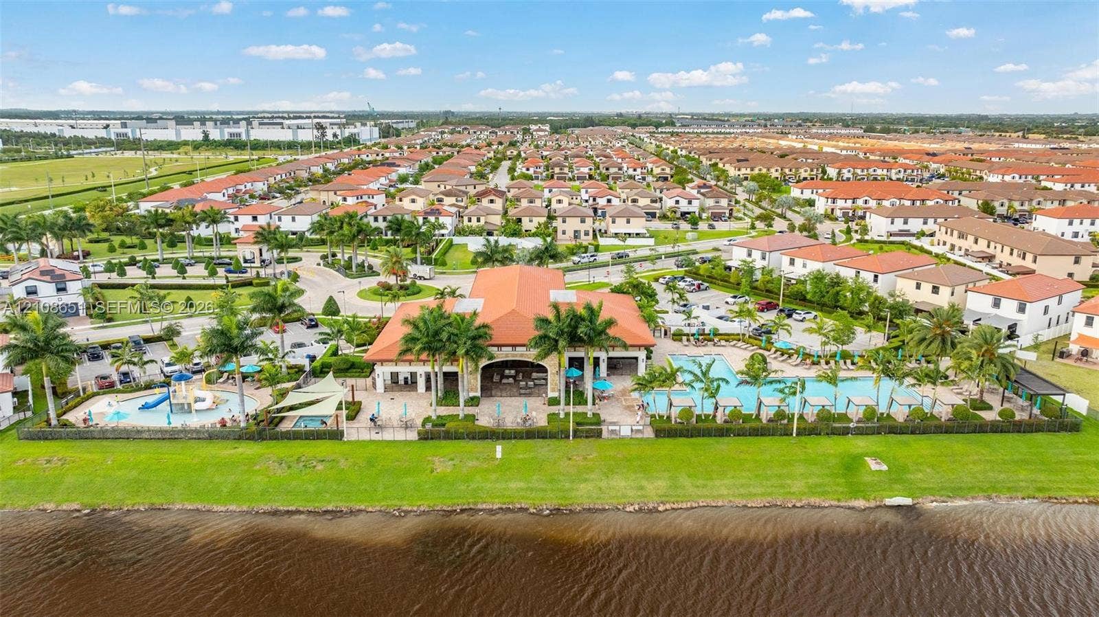 3288 W 106th Terrace, #3288, Hialeah, Hialeah, FL 33018 Community clubhouse featuring a swimming pool, childrens splash area with slide, paved patio space, and direct waterfront access
