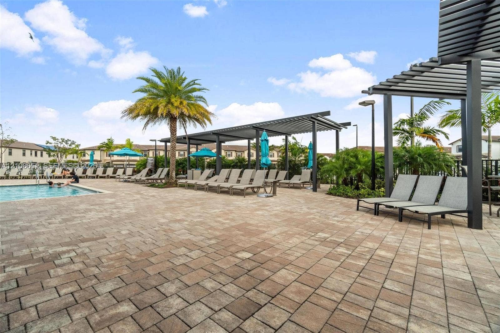 3288 W 106th Terrace, #3288, Hialeah, Hialeah, FL 33018 Community swimming pool featuring paved decking, metal pergola structures, and mature palm trees