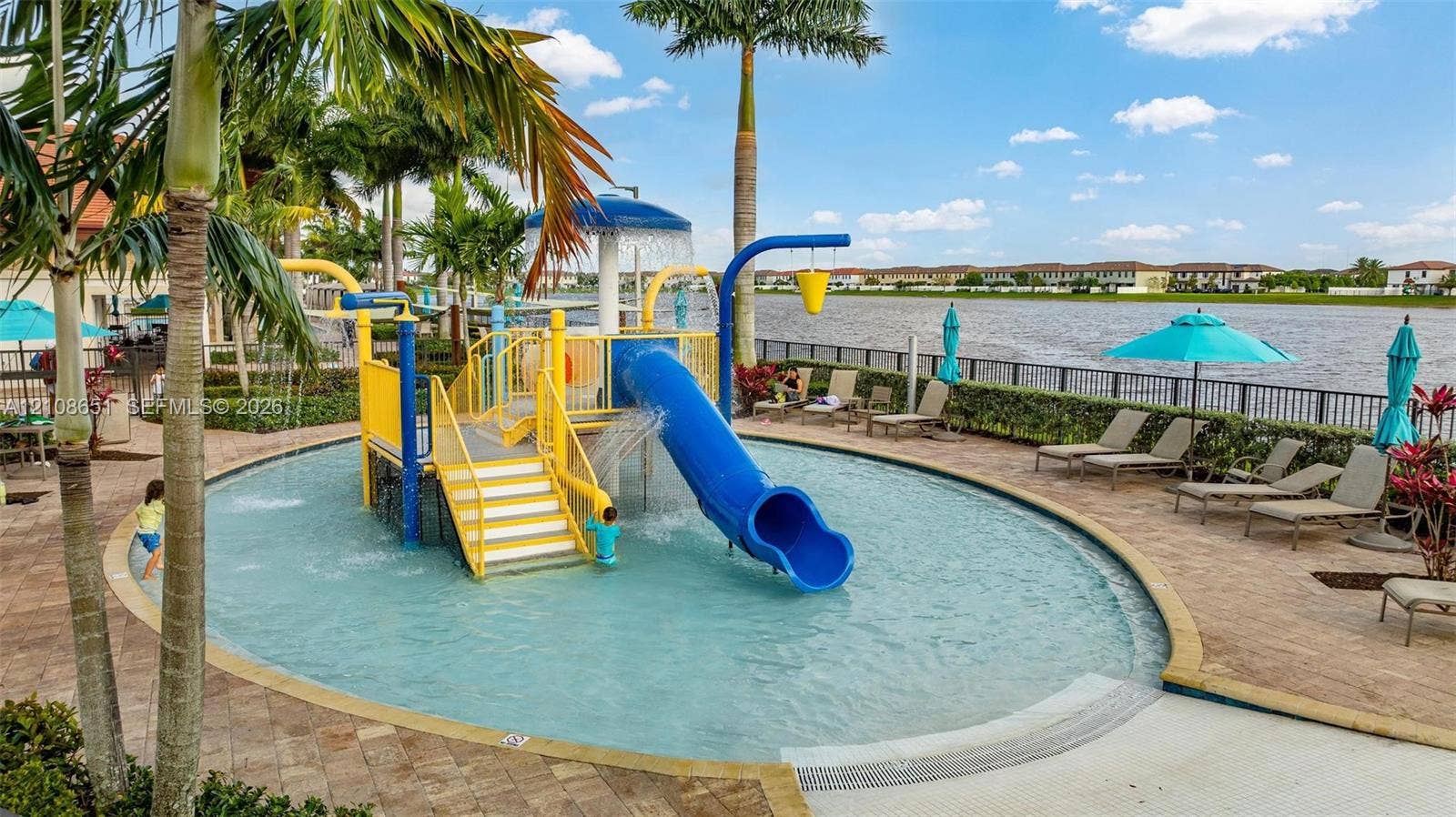 3288 W 106th Terrace, #3288, Hialeah, Hialeah, FL 33018 Waterfront community recreation area featuring a shallow-entry pool, integrated water slide, splash pad structure, and stone paver surround