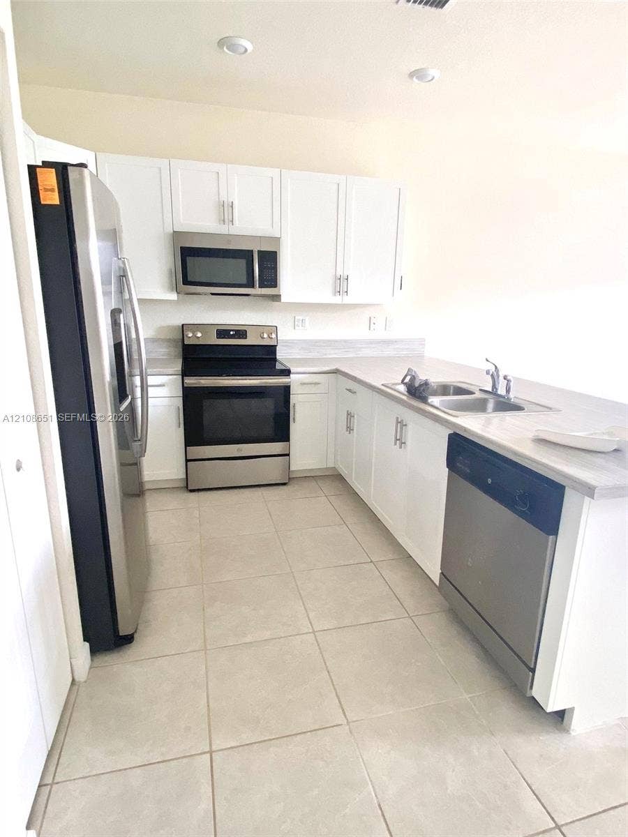 3288 W 106th Terrace, #3288, Hialeah, Hialeah, FL 33018 Kitchen featuring white shaker-style cabinetry, stainless steel appliances, recessed lighting, tile flooring, and a dual-basin stainless steel sink