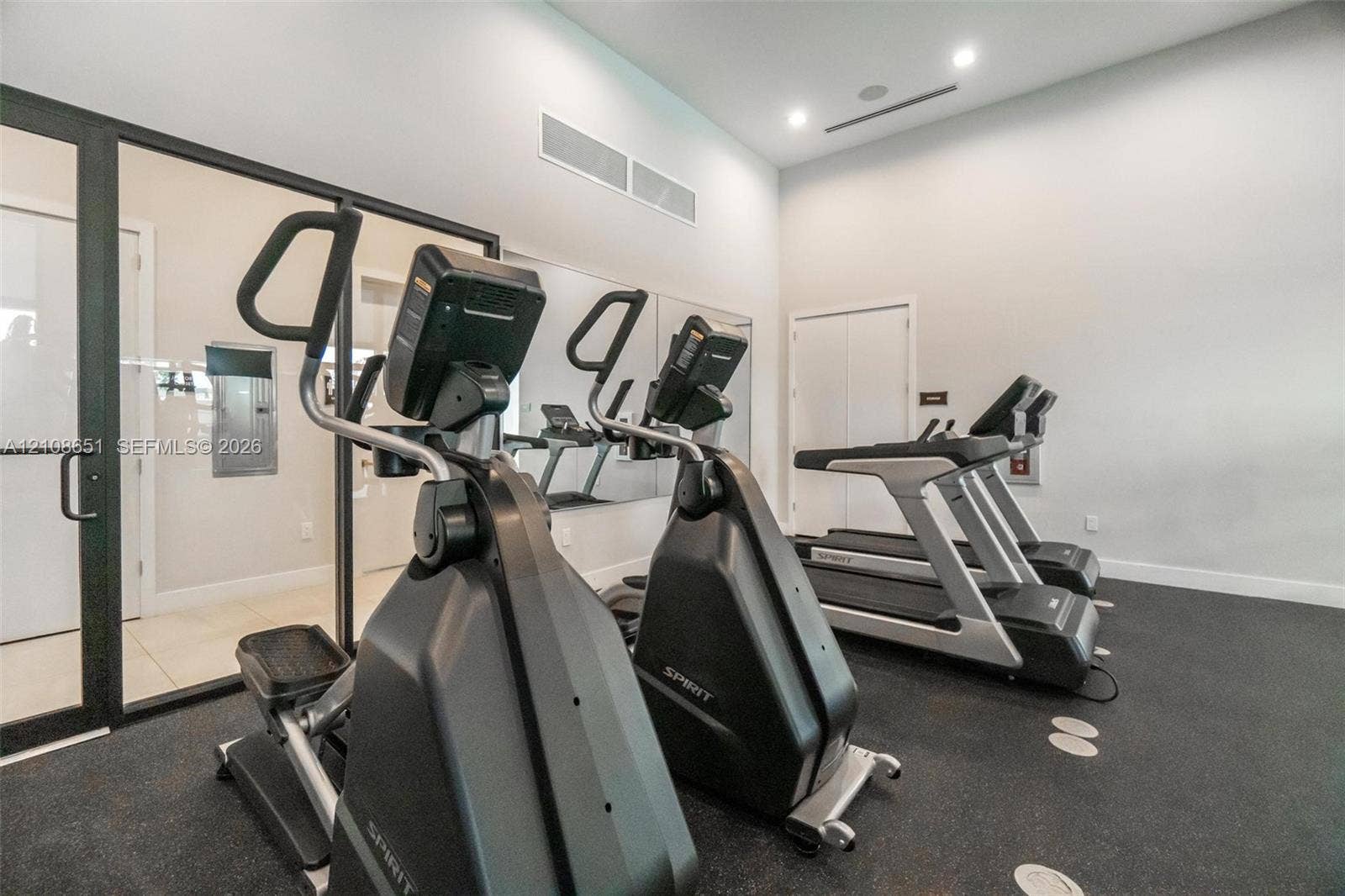 3288 W 106th Terrace, #3288, Hialeah, Hialeah, FL 33018 Fitness room featuring high ceilings, recessed lighting, full-wall mirrors, and black rubberized flooring enclosed by floor-to-ceiling glass paneling
