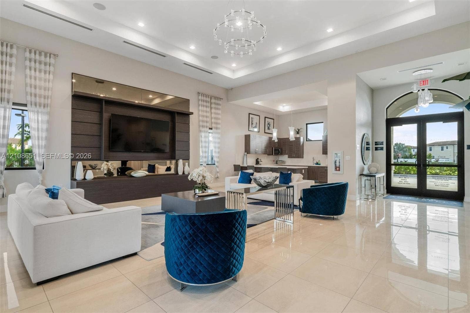 3288 W 106th Terrace, #3288, Hialeah, Hialeah, FL 33018 Tray ceiling with integrated recessed lighting, polished large-format tile flooring, built-in media center with dark wood cabinetry, chandelier light fixtures, and glass-paned double entry doors with arched transom