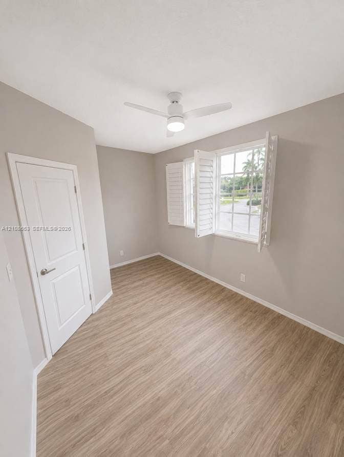 291 Duval Court, #0, Weston, Weston, FL 33326 Room featuring wood-finish flooring, white plantation shutters, a white paneled door, and a ceiling fan with integrated lighting