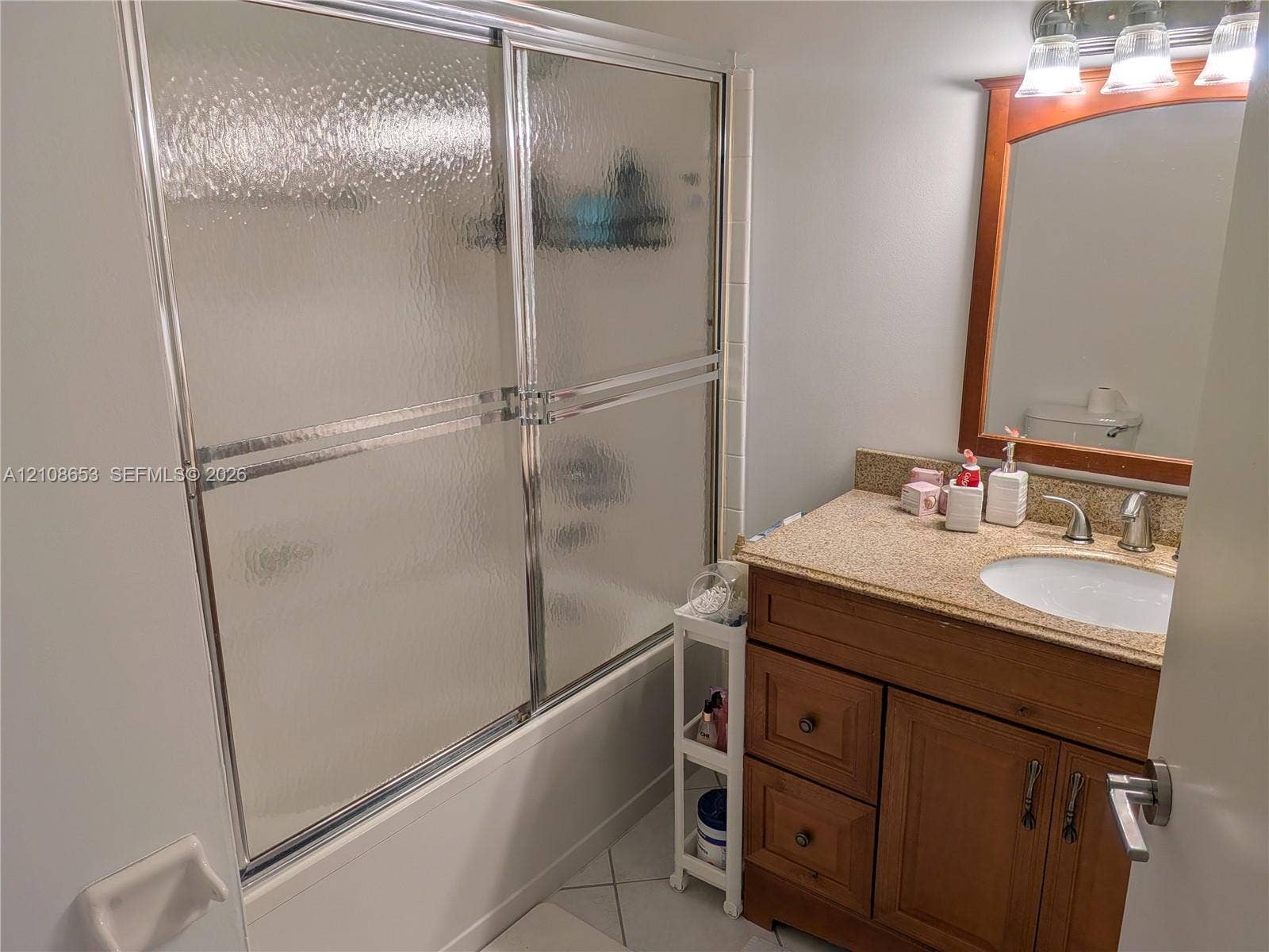 291 Duval Court, #0, Weston, Weston, FL 33326 Bathroom featuring a wood vanity with a stone-finish countertop, integrated sink, metal-framed sliding glass shower door, and a wooden-framed wall mirror with integrated lighting