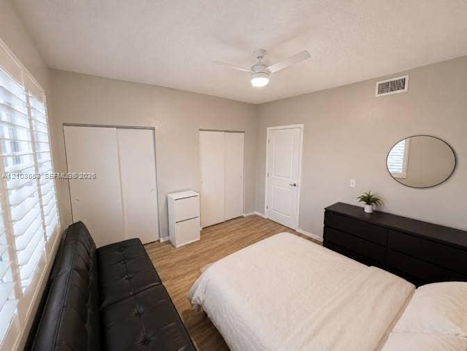 291 Duval Court, #0, Weston, Weston, FL 33326 Interior space featuring wood-finish flooring, white plantation shutters, dual reach-in closets with white paneled doors, and a ceiling-mounted fan with integrated light