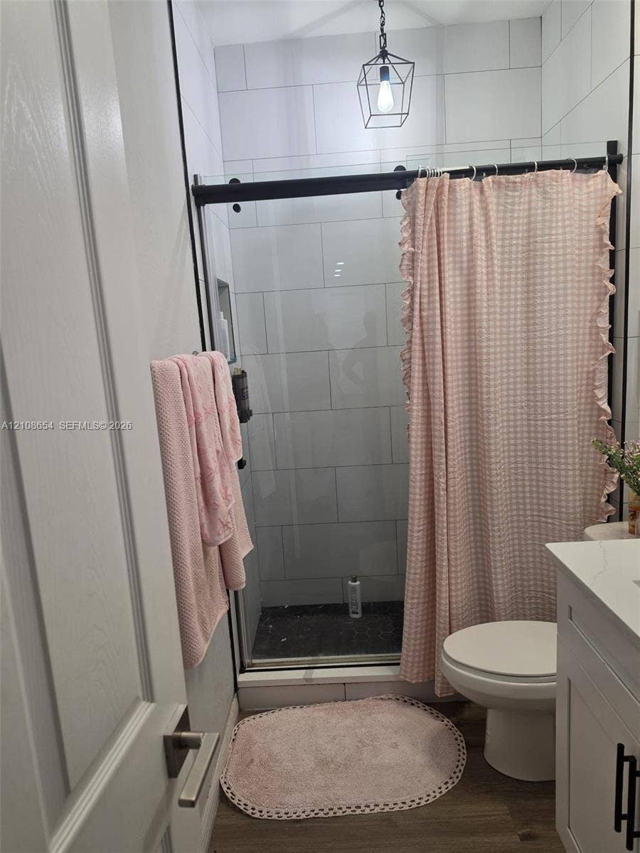 1225 SW 35 Terrace, Cape Coral, FL 33914 Walk-in shower with matte black sliding glass hardware and light-toned subway tile surround, complemented by a white vanity with light-toned solid surface countertop and a geometric pendant light fixture