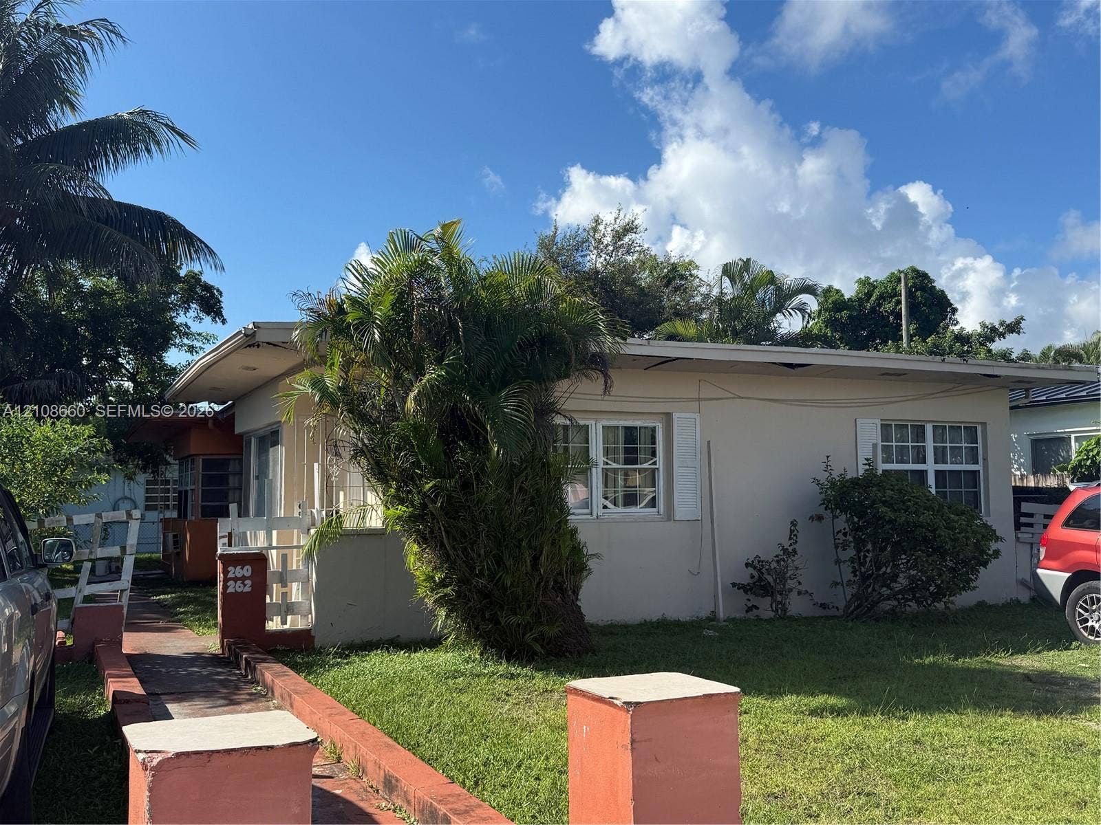 262 NE 111th Street, Miami, FL 33161 Single-story exterior featuring light-colored stucco siding, grid-pattern windows with shutters, and mature landscaping