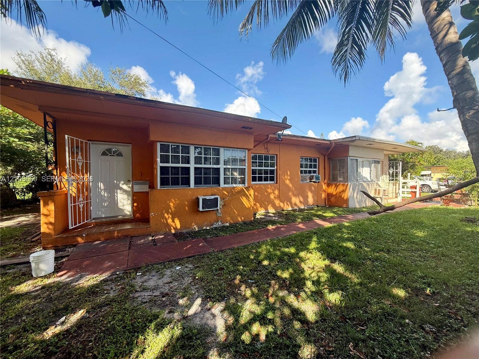 262 NE 111th Street, Miami, FL 33161 Single-story exterior featuring a stucco facade, metal security screen door, multi-pane windows, and a paved walkway