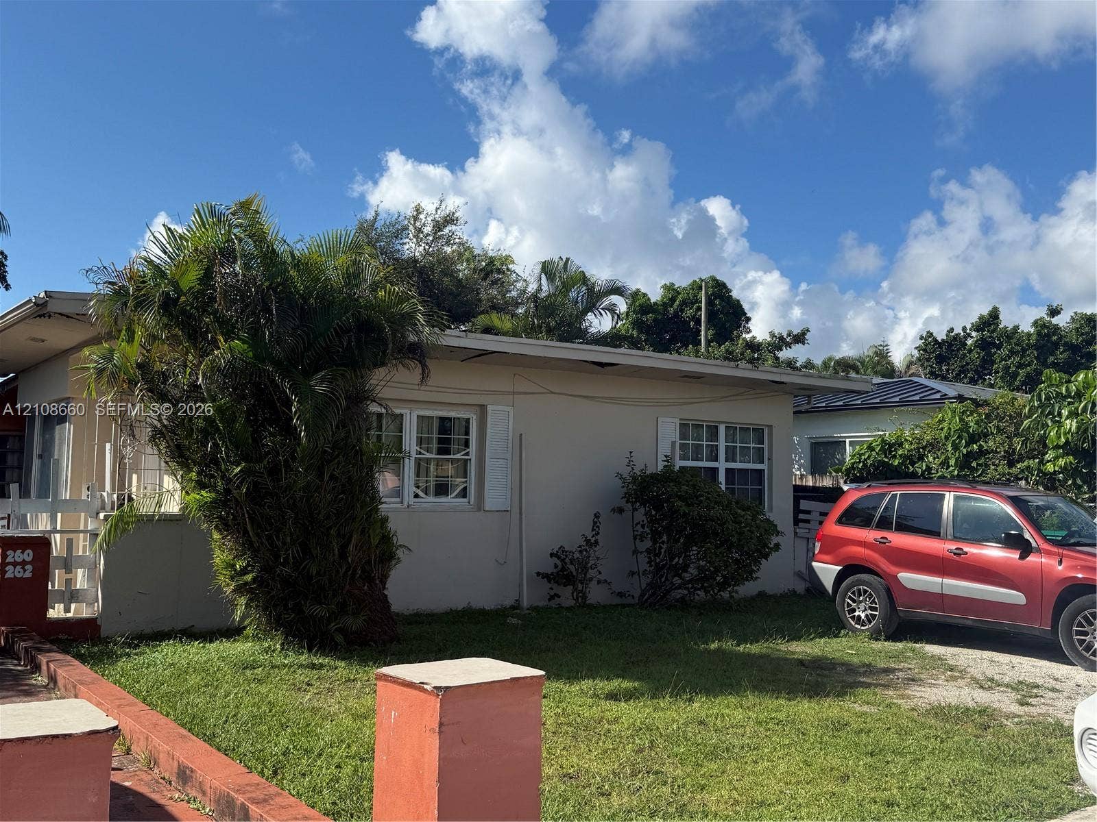 262 NE 111th Street, Miami, FL 33161 Single-story exterior featuring a flat roofline, stucco-finish siding, multi-pane windows with shutters, and a front yard with mature palm landscaping