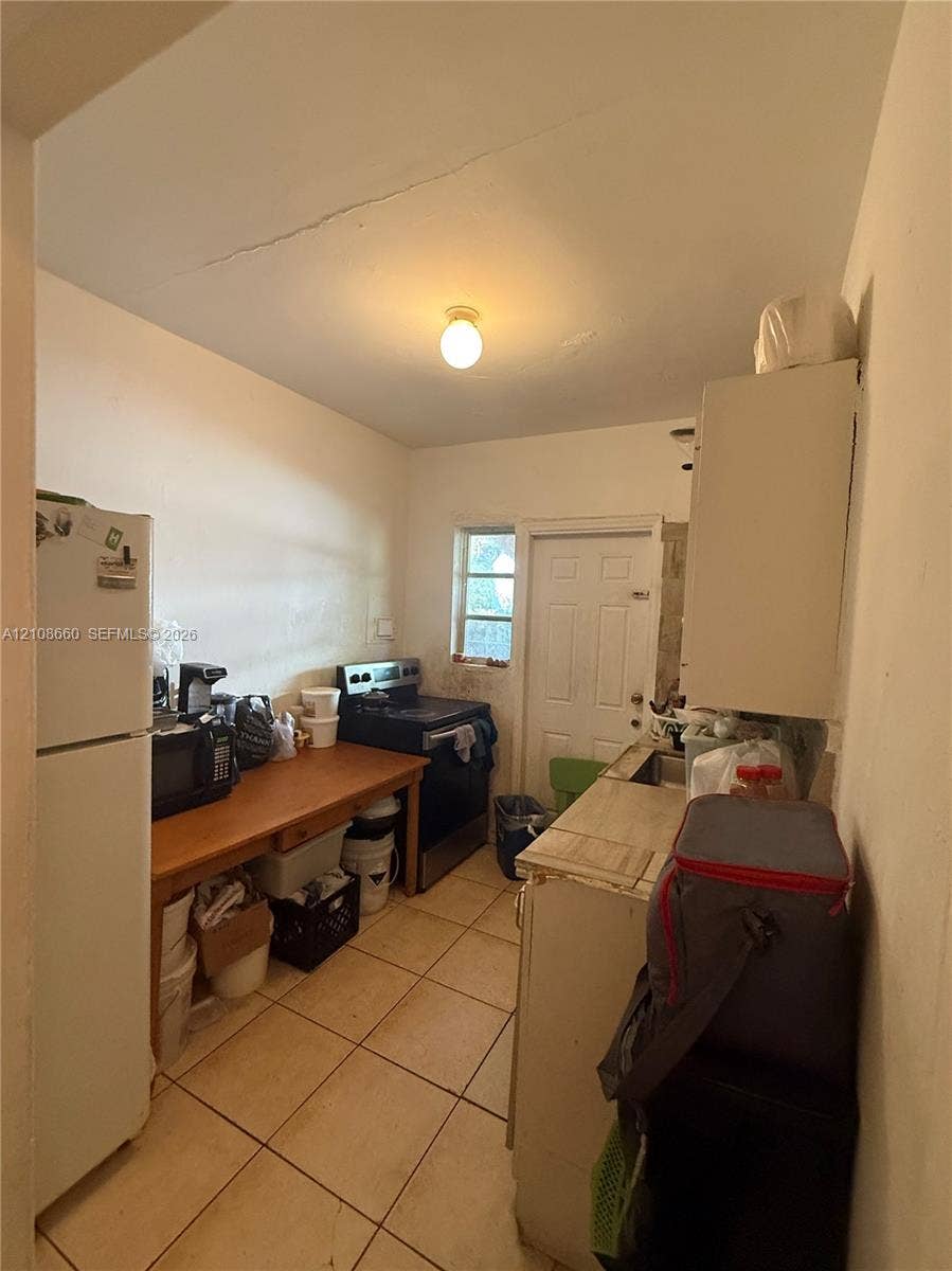 262 NE 111th Street, Miami, FL 33161 Kitchen featuring ceramic tile flooring, a multi-panel exterior door with glass insert, and a single-light ceiling fixture