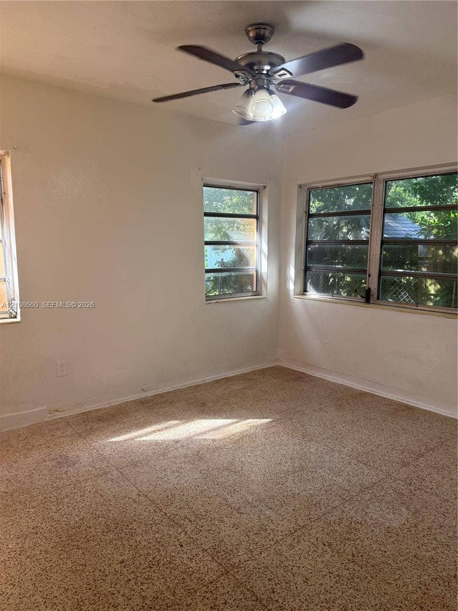 262 NE 111th Street, Miami, FL 33161 Interior space featuring light-toned tile flooring, multi-pane casement windows, and a ceiling-mounted fan with integrated light fixture