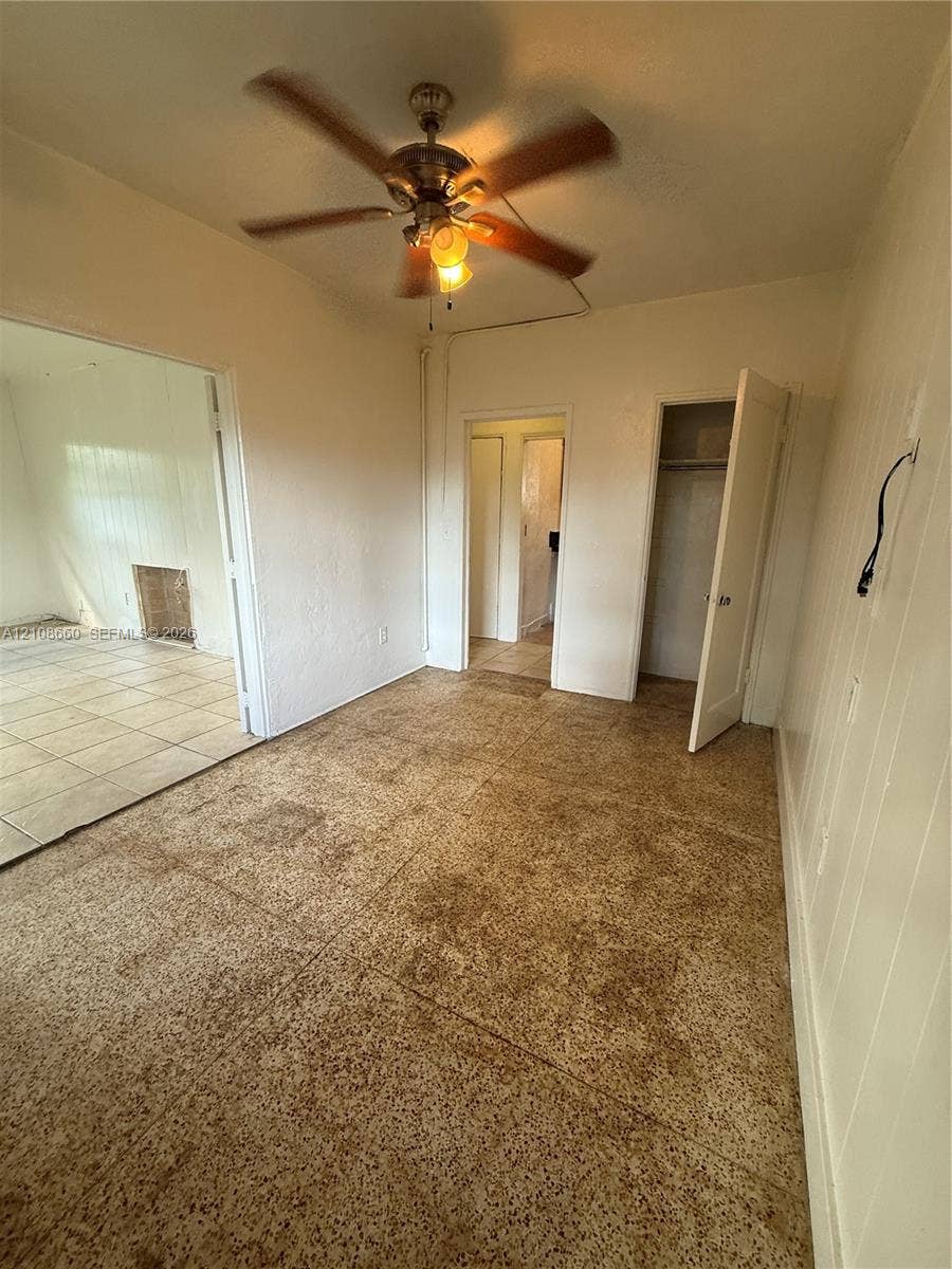 262 NE 111th Street, Miami, FL 33161 Room featuring textured flooring, ceiling fan with integrated lighting, and built-in closet storage
