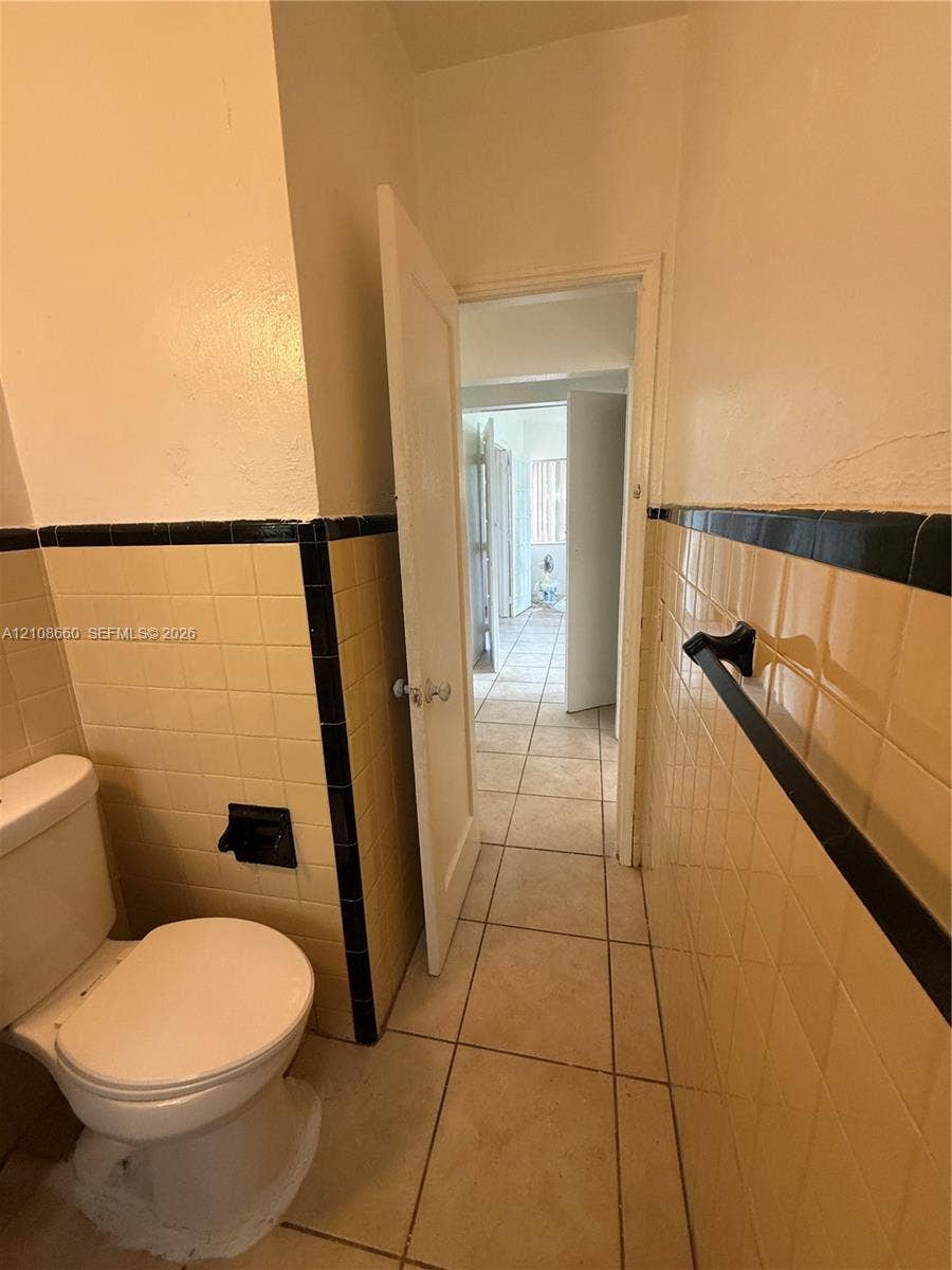 262 NE 111th Street, Miami, FL 33161 Ceramic wall tile featuring a decorative black border, tile flooring, and a wall-mounted towel bar