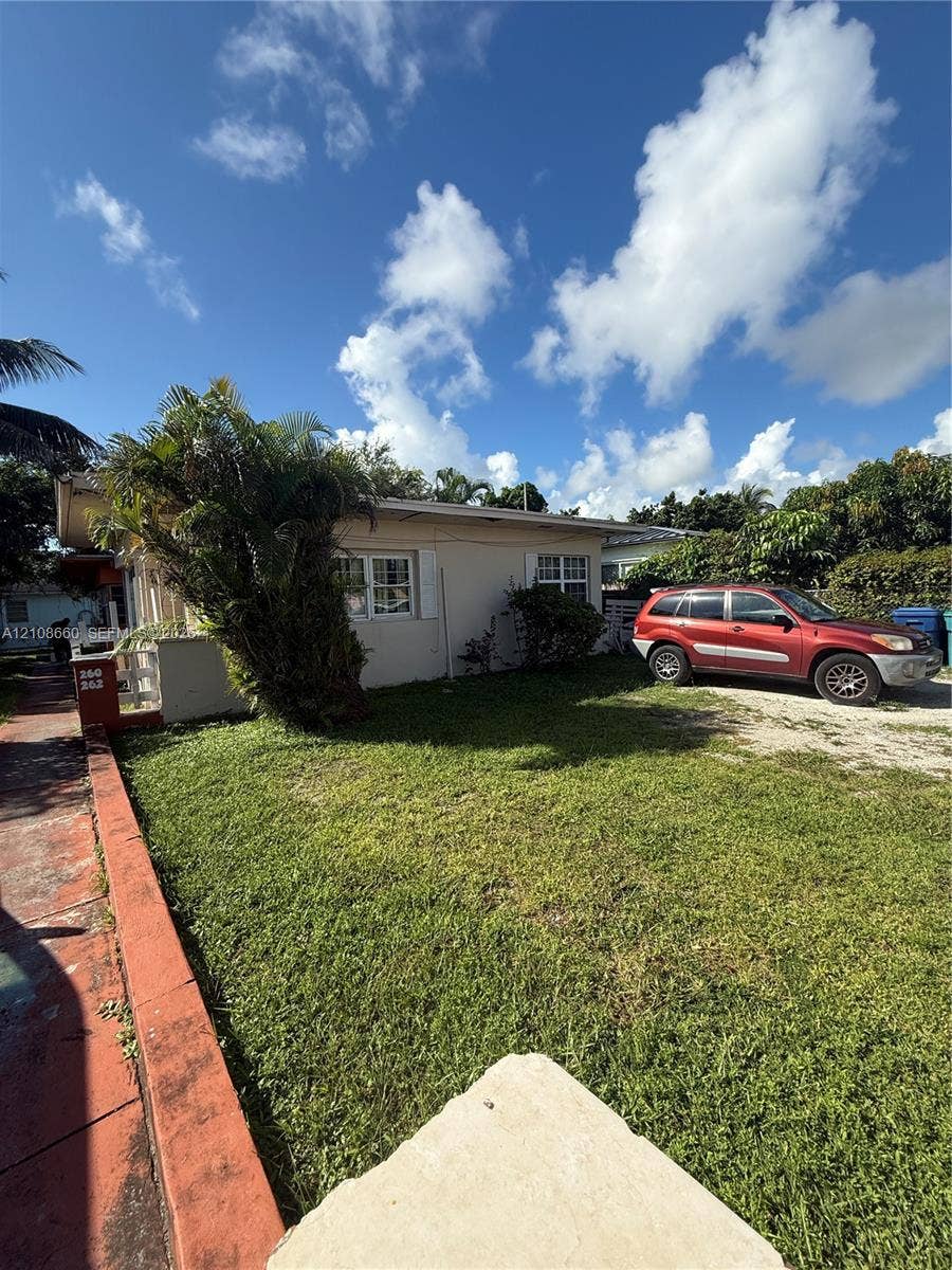 262 NE 111th Street, Miami, FL 33161 Single-story residence featuring light-toned stucco exterior, multi-pane windows, and a dedicated gravel surface parking area