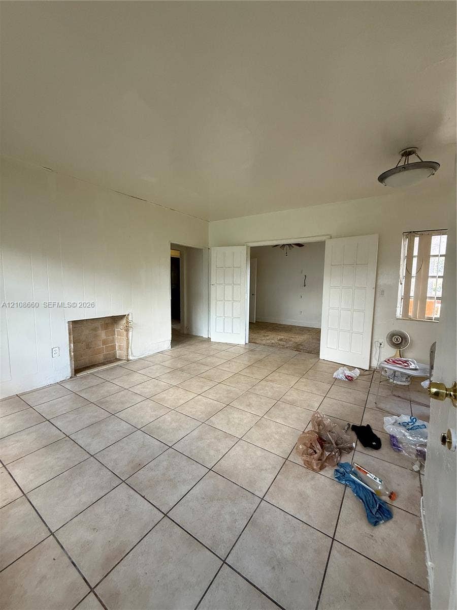 262 NE 111th Street, Miami, FL 33161 Neutral-toned tile flooring, masonry fireplace hearth, and double French doors with glass panes