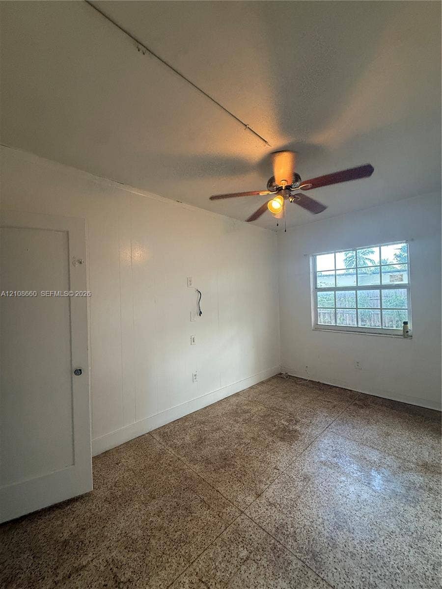 262 NE 111th Street, Miami, FL 33161 Room featuring light-toned flooring, a multi-pane window, and a ceiling fan with integrated lighting