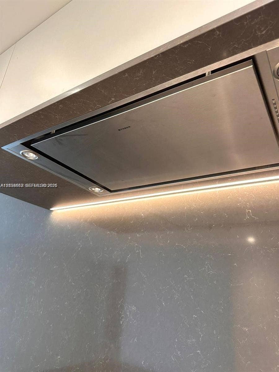 300 Biscayne Boulevard, #2709W, Miami, Miami, FL 33131 Stainless steel range hood integrated into a custom enclosure featuring solid-surface surfacing, recessed task lighting, and under-cabinet strip lighting