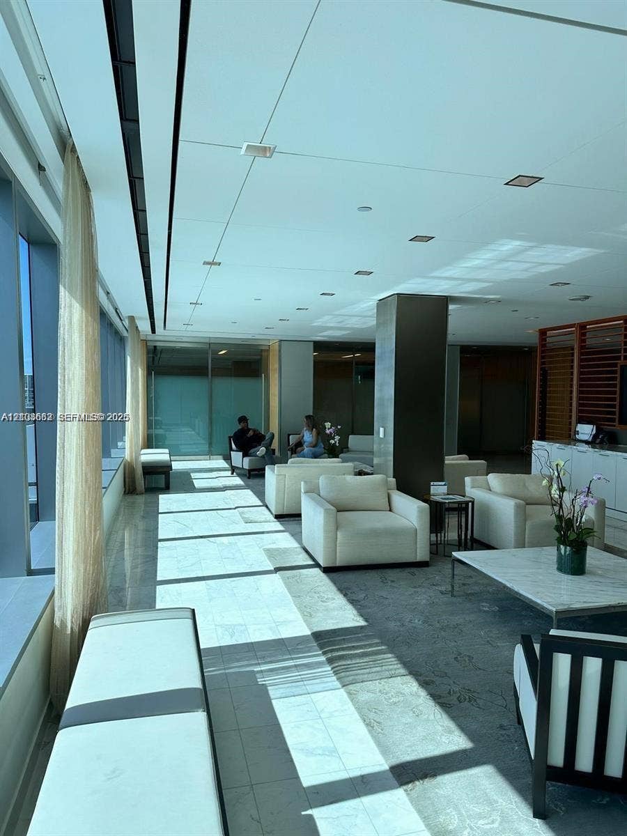 300 Biscayne Boulevard, #2709W, Miami, Miami, FL 33131 Open-concept common area featuring floor-to-ceiling windows, polished stone flooring, recessed ceiling lighting, and a prominent structural pillar
