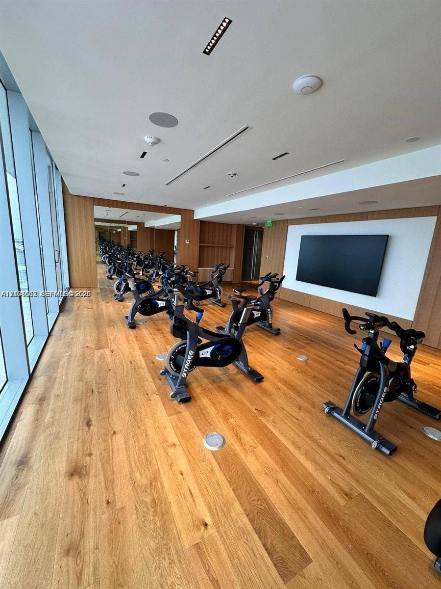 300 Biscayne Boulevard, #2709W, Miami, Miami, FL 33131 Fitness room featuring floor-to-ceiling windows, wood-finish flooring, full-wall mirrors, recessed lighting, and integrated wall-mounted display