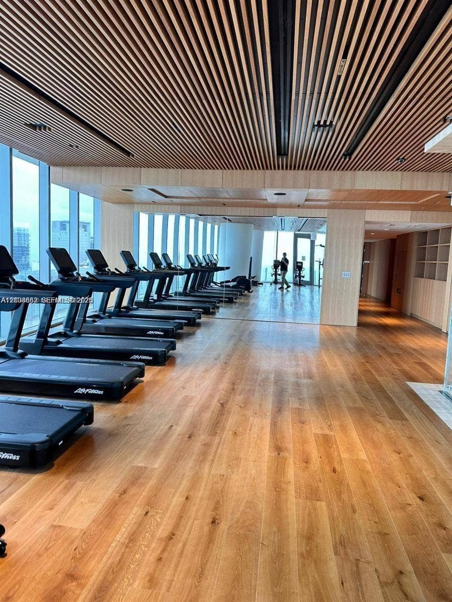 300 Biscayne Boulevard, #2709W, Miami, Miami, FL 33131 Fitness facility featuring linear wood-slat ceiling detailing, floor-to-ceiling windows, wood-finish flooring, and built-in wall shelving