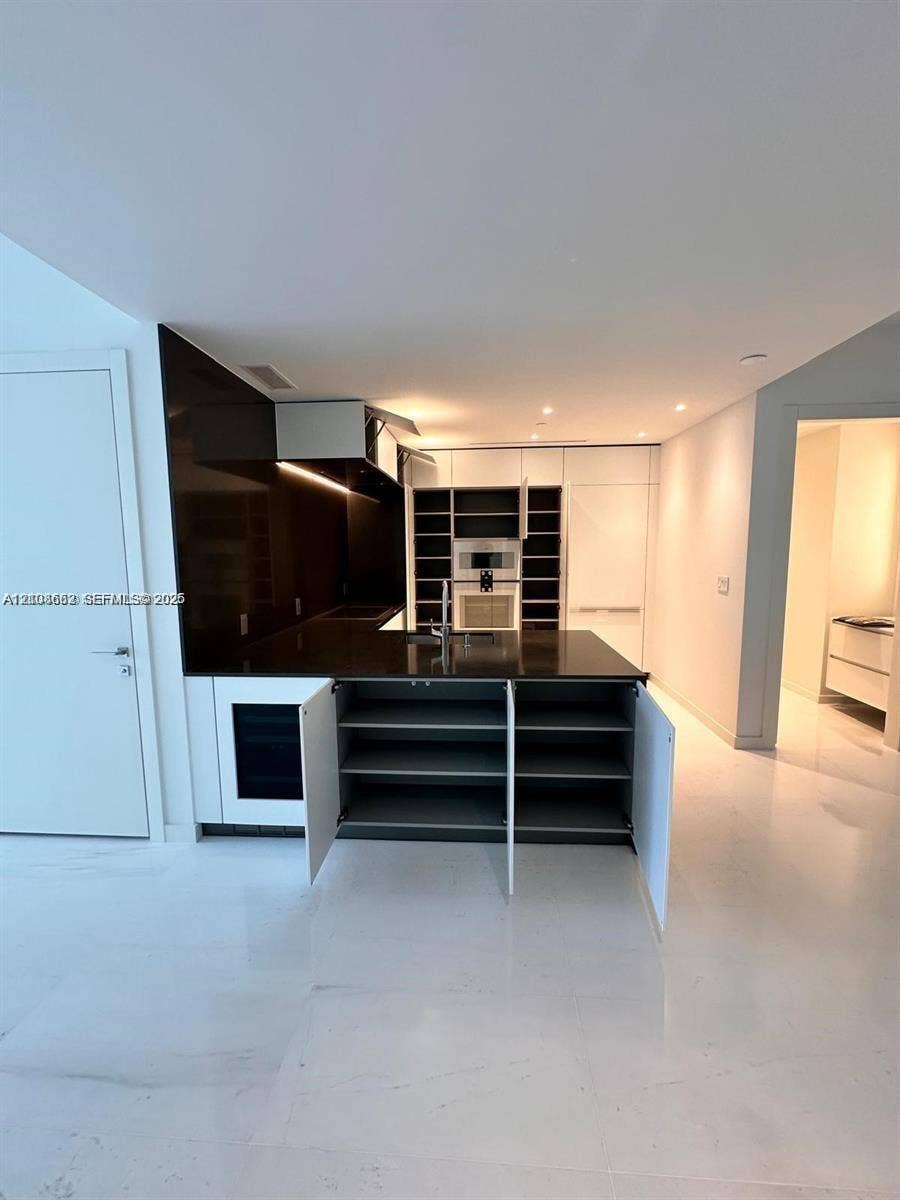 300 Biscayne Boulevard, #2709W, Miami, Miami, FL 33131 Kitchen featuring high-contrast cabinetry, integrated appliances, dark stone-finish countertops, an under-counter wine cooler, and polished light-toned flooring