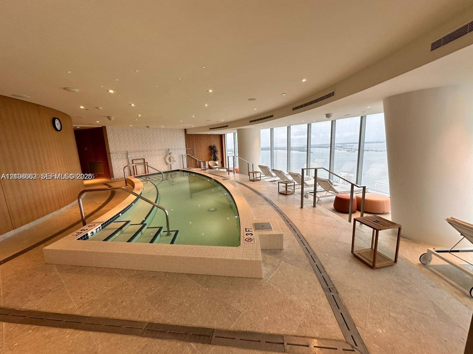 300 Biscayne Boulevard, #2709W, Miami, Miami, FL 33131 Indoor swimming pool featuring floor-to-ceiling windows, natural stone tile flooring, perimeter LED recessed lighting, wood-paneled walls, and built-in metal handrails