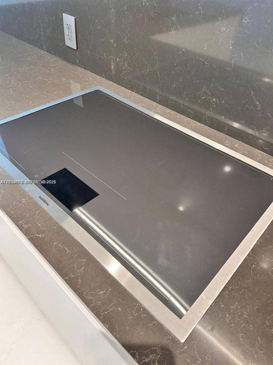 300 Biscayne Boulevard, #2709W, Miami, Miami, FL 33131 Flush-mount induction cooktop featuring a sleek glass surface with a stainless steel trim, integrated into a neutral-toned countertop with a matching slab backsplash