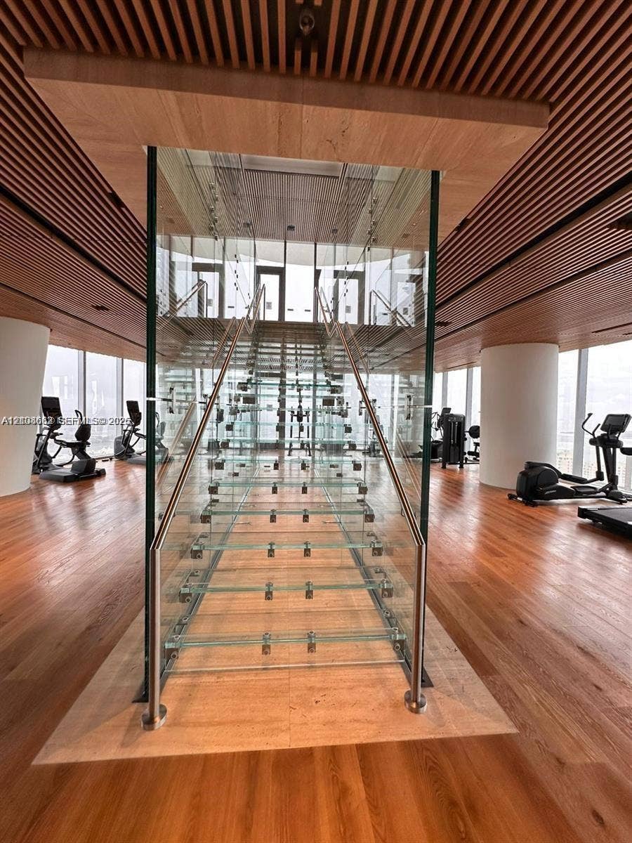 300 Biscayne Boulevard, #2709W, Miami, Miami, FL 33131 Staircase featuring glass treads and stainless steel railings, encased in a glass structural surround, complemented by a slatted wood ceiling, wood-finish flooring, and floor-to-ceiling windows