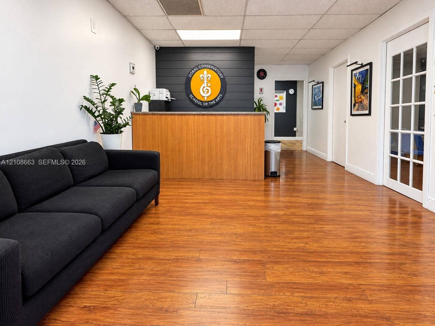Doral, Doral, FL 33166 Reception area featuring wood-finish flooring, a wood-finish built-in desk with a stone countertop, a charcoal shiplap accent wall, and a multi-pane glass door