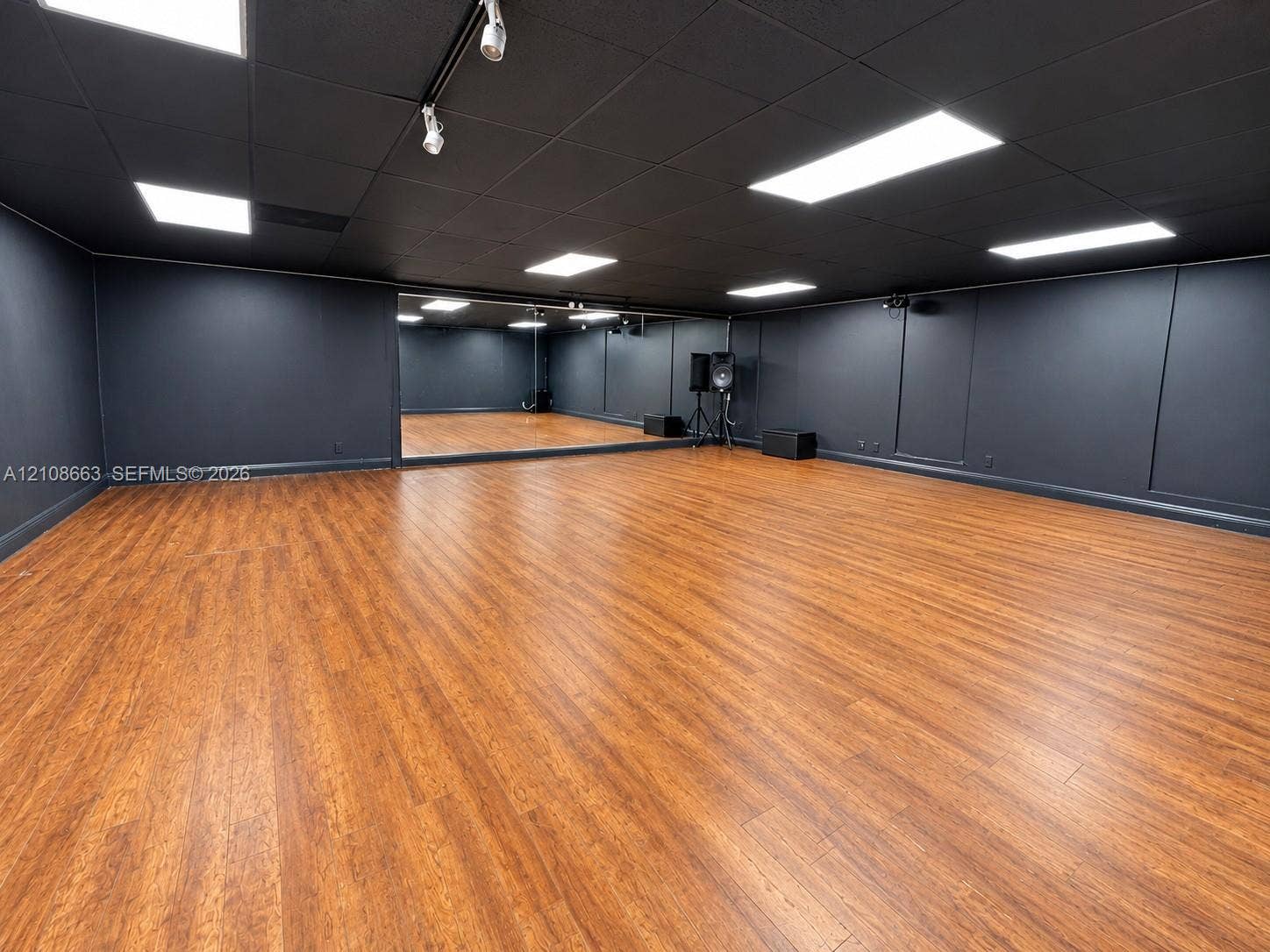 Doral, Doral, FL 33166 Expansive multi-purpose room featuring wood-finish flooring, full-wall mirrors, recessed lighting, and a dark-toned drop ceiling