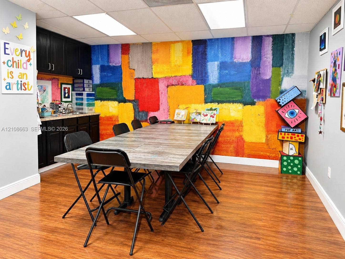 Doral, Doral, FL 33166 Room featuring wood-finish flooring, drop ceiling with recessed lighting, black built-in cabinetry, and a countertop with an integrated sink