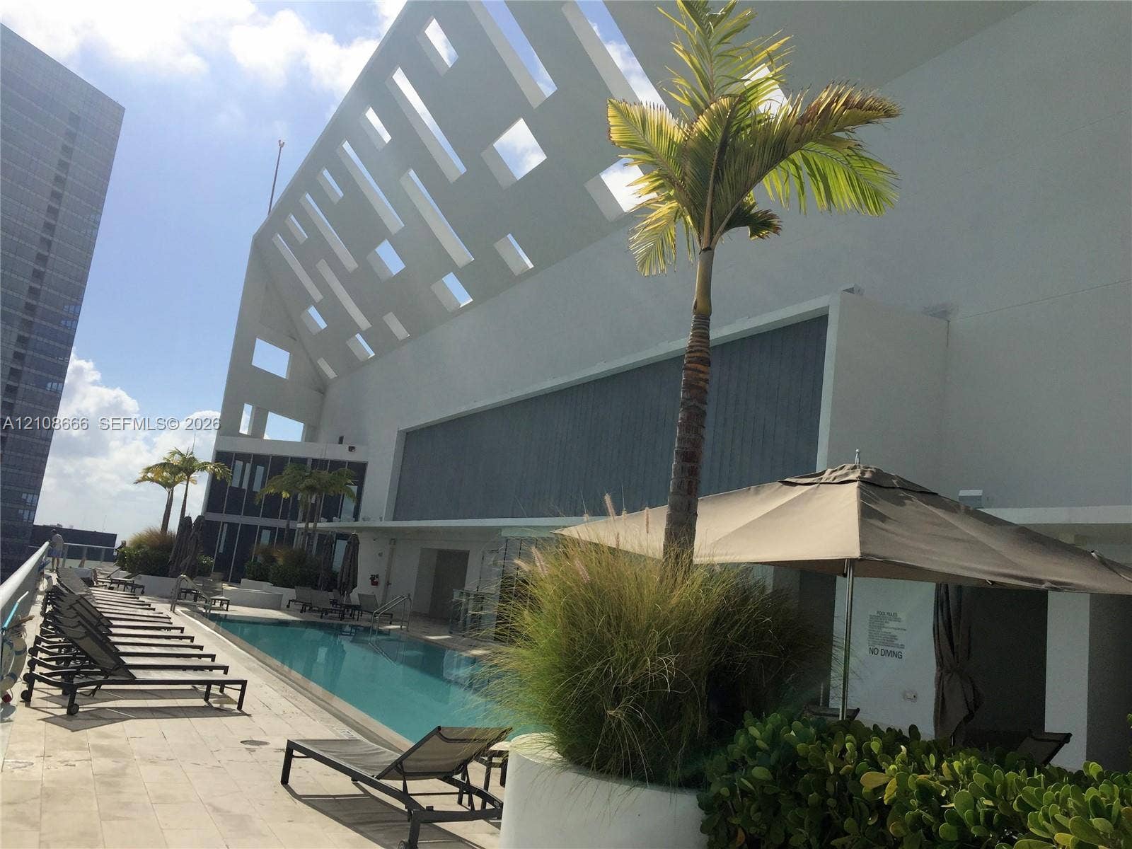 1300 Brickell Bay Drive, #3506, Miami, FL 33131 Rooftop swimming pool featuring a concrete deck, architectural geometric screening, and integrated landscaping planters