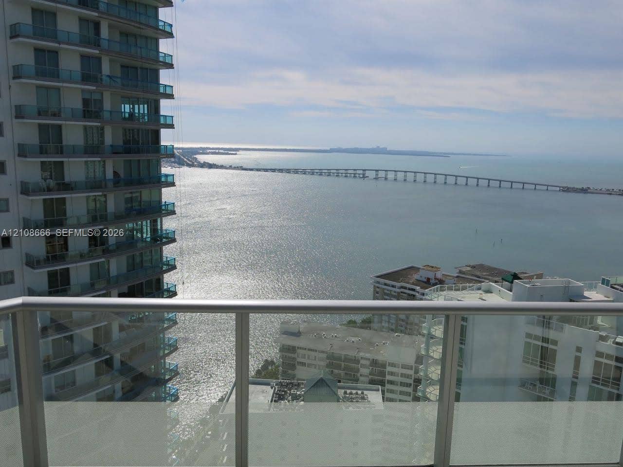 1300 Brickell Bay Drive, #3506, Miami, FL 33131 Balcony featuring glass railings, metal framing, and direct water and bridge scenery