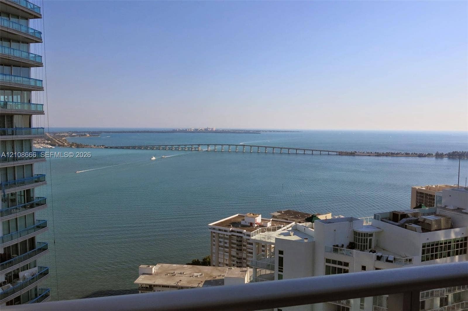 1300 Brickell Bay Drive, #3506, Miami, FL 33131 Elevated balcony with a horizontal metal railing overlooking a maritime horizon, bridge, and coastal cityscape
