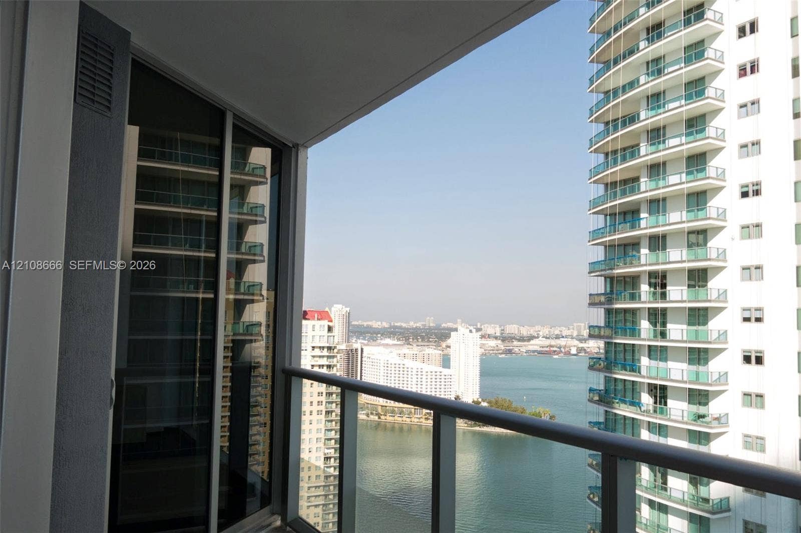 1300 Brickell Bay Drive, #3506, Miami, FL 33131 Private balcony with a metal and glass railing, floor-to-ceiling glass sliding door, and urban and water scenery