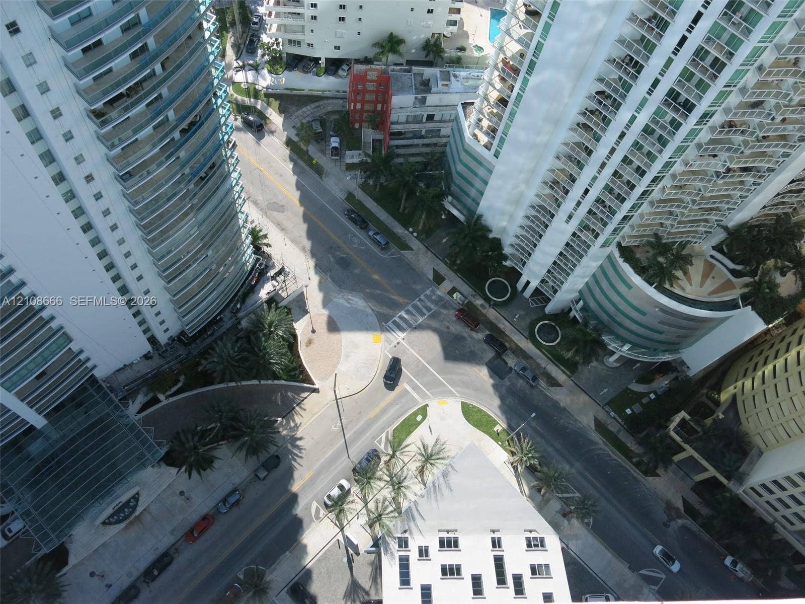1300 Brickell Bay Drive, #3506, Miami, FL 33131 High-rise urban setting featuring tiered glass balconies, multi-story structural architecture, palm tree landscaping, and paved street-level infrastructure