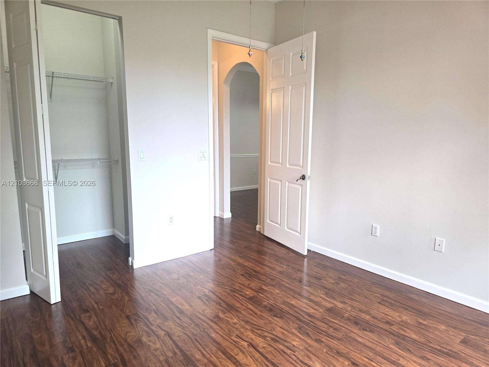 4508 SW 160th Avenue, #734, Miramar, Miramar, FL 33027 Room featuring wood-finish flooring, a multi-panel door, an arched entryway, and a built-in closet with wire shelving