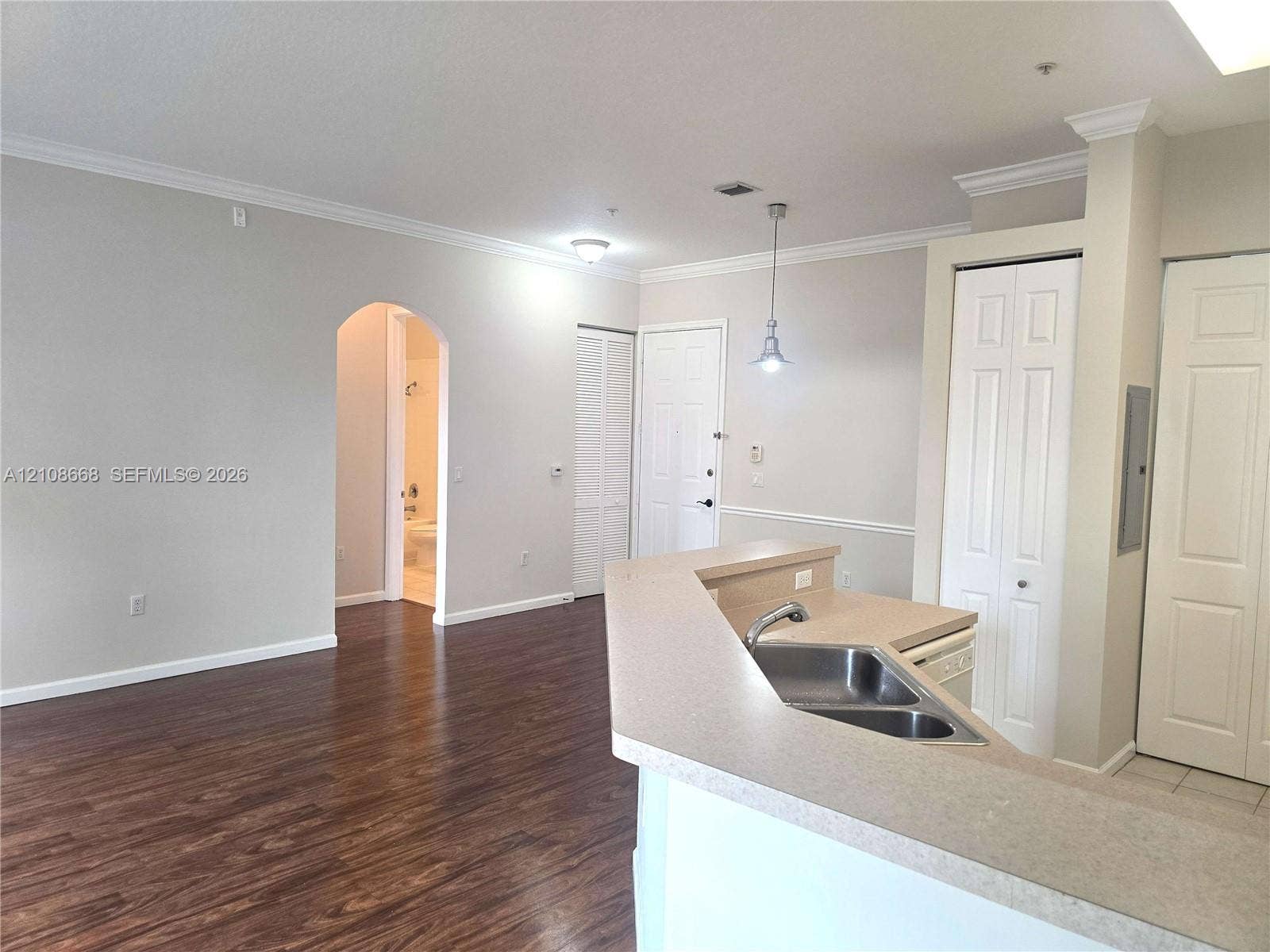 4508 SW 160th Avenue, #734, Miramar, Miramar, FL 33027 Open-concept interior featuring wood-finish flooring, a kitchen breakfast bar with integrated double-basin stainless steel sink, crown molding, and an arched entry