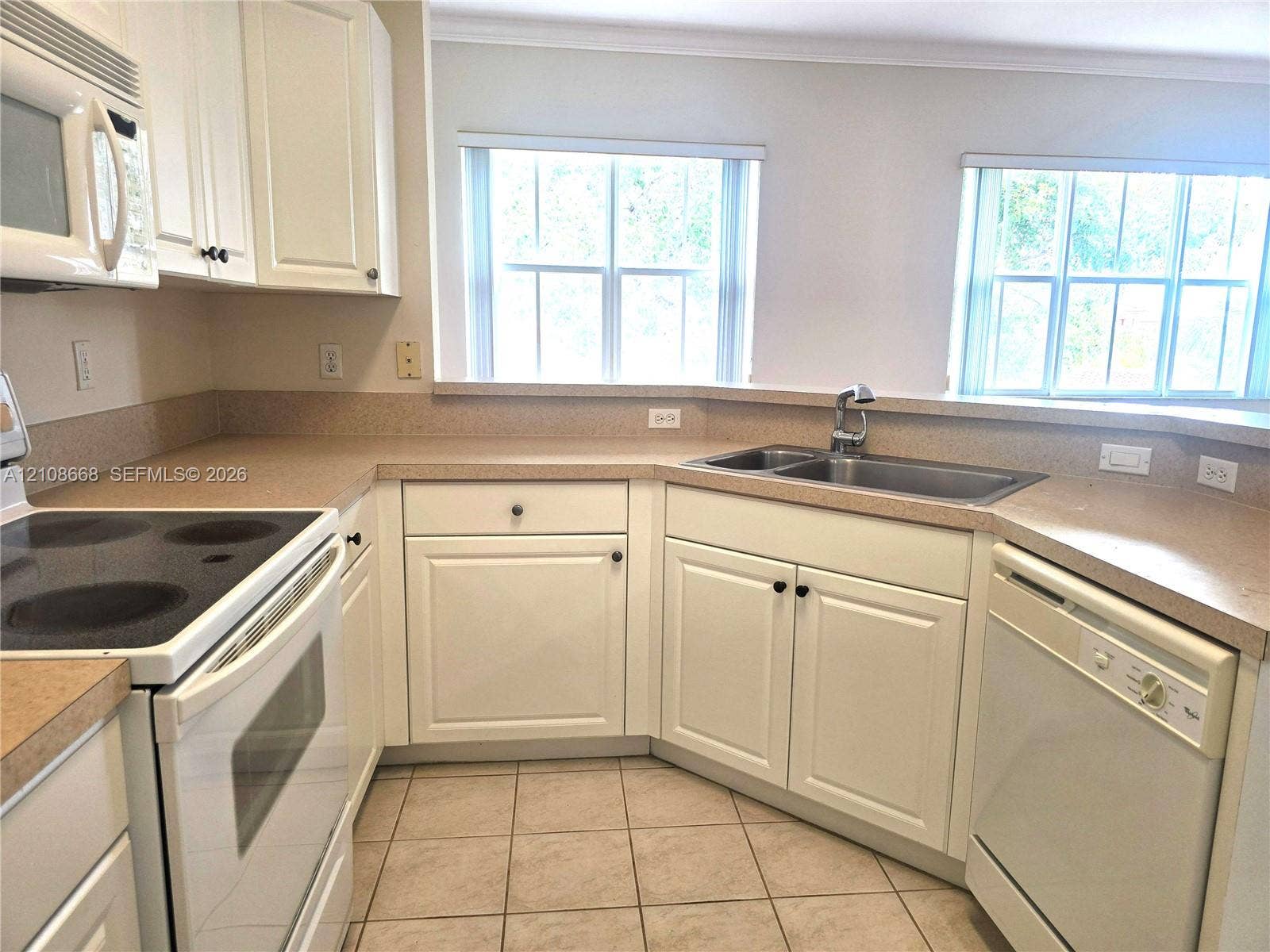 4508 SW 160th Avenue, #734, Miramar, Miramar, FL 33027 Kitchen featuring white shaker-style cabinetry, solid-surface countertops, a stainless steel double-basin sink, and ceramic tile flooring